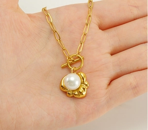 Dettaglio di elegante collana in titanio dorato con grande perla e chiusura a levetta