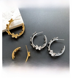 Detailed view of gold and silver plated butterfly hoop earrings on stone display