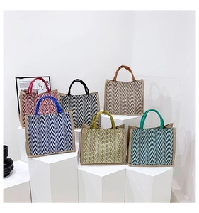 Collection of striped woven tote bags in six colors displayed on geometric blocks