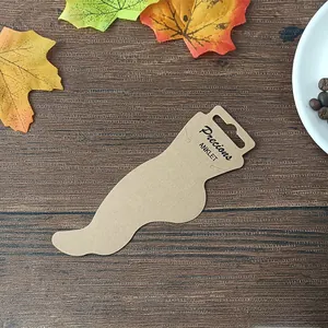 Brown kraft paper anklet display card with Precious Anklet text on a wooden desk