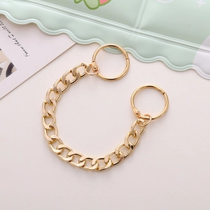 Detailed view of a gold chunky metal chain charm accessory on a pastel background