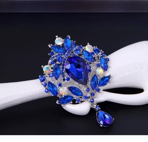 Close-up of luxury royal blue crystal brooch with pear-shaped stones and teardrop pendant