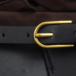 Detailed close-up of a black leather belt with a vintage golden U-shaped buckle