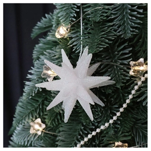 Sparkling white star Christmas ornament hanging on a festive tree with warm lights
