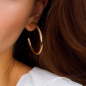 Polished gold-plated C-shaped hoop earrings worn by a model for a stylish look