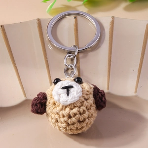 Handmade crochet puppy keychain in light brown yarn on a minimalist ceramic plate