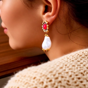 Detailaufnahme der Vintage-Gold-Blumenohrringe mit roten Blättern und einer weißen Perle