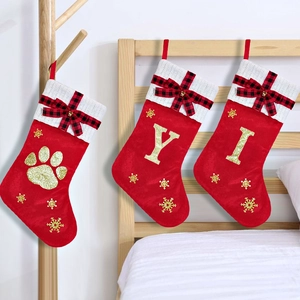 Detail of red Christmas stockings with sequin letters, plaid bows and metal bells