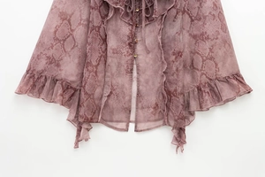 Detail of snake print chiffon blouse featuring golden buttons and ruffle layered hemline