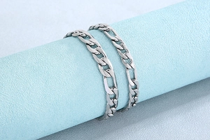 Vue détaillée des bracelets à mailles Figaro en acier argenté avec finition polie