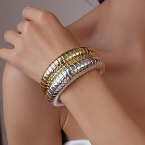 Detailed view of layered gold and silver wide bangles with unique spiral texture on wrist