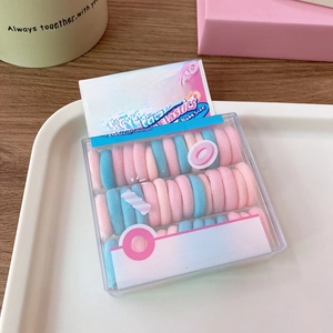 Detail of baby hair elastics in macaroon colors inside a clear cereal style box packaging