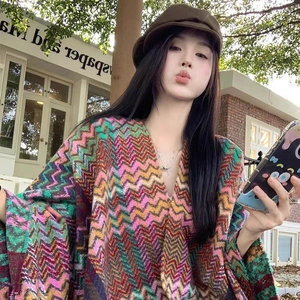 Ethnic knit poncho with colorful zigzag patterns, tassel edges, and cozy hooded design