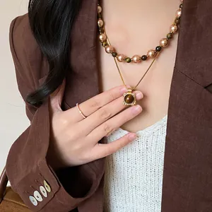 Detail of layered gold necklace with tiger eye stone pendant and pearl beaded chain