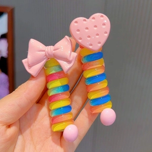 Close-up of pink bow and heart hair clips with rainbow spiral coils for kids