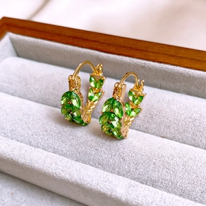 Close-up of vintage emerald stud earrings with gold leaf design in a velvet jewelry box