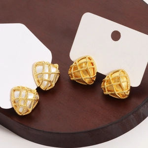 Detail of woven heart and triangular stud earrings with gold finish and pearl inlay