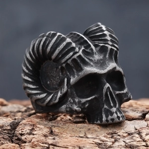 Close-up of vintage ram skull ring with curved horns on a natural tree bark texture