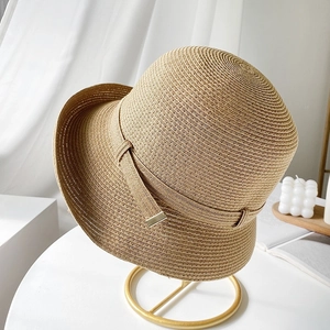 Cappello di paglia da donna con trama fine ed eleganti dettagli in metallo dorato su supporto