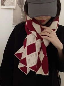 Détail de la texture de l'écharpe en maille losange rouge et crème sur mannequin
