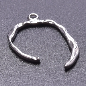 Macro shot of silver stainless steel C-ring pendant with irregular hammered texture detail