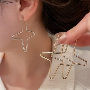 Close-up of minimalist geometric four-pointed star earrings in gold and silver finish