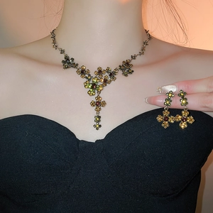Detailed view of model wearing vintage gold flower cross jewelry set with colored gems