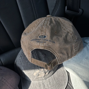Detail of vintage washed canvas baseball cap featuring retro embroidery and metal buckle