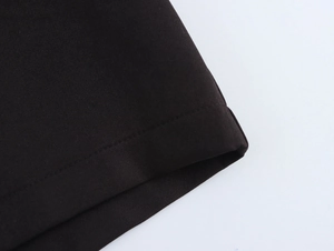 Detailed view of black fabric texture with neat stitching on hem of low rise shorts