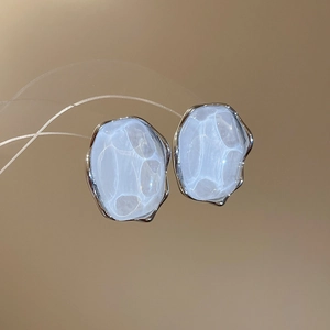 Macro shot of French resin oval earrings with translucent water ripple pattern and silver frame