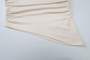 Détail du haut ajusté beige montrant l'ourlet froncé irrégulier et la texture du tissu