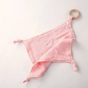 Detalle de mantita de apego de muselina de algodón rosa con anillo de dentición de madera