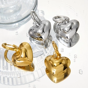Polished hollow heart earrings in gold and silver finish on mirror background