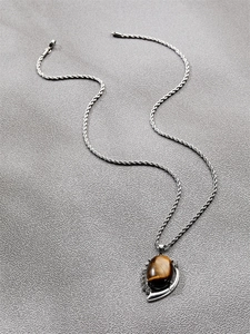 Detail of silver twisted chain necklace with a crescent-set brown tiger eye stone pendant