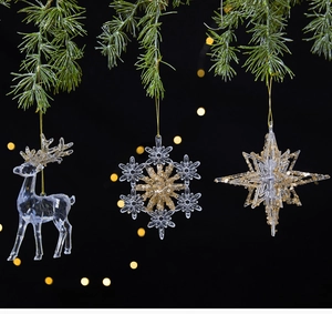 Transparent acrylic Christmas ornaments with gold sequins hanging on pine branches