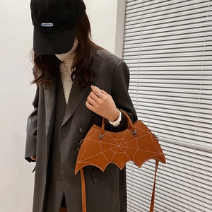 Brown PU leather bat-shaped handbag with spider web embroidery detail on casual outfit