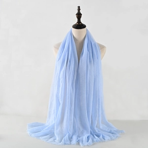 Detail of light blue wrinkled cotton linen scarf with soft texture and frayed edges