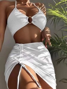 Close-up of white bikini top with gold ring and textured drawstring beach skirt