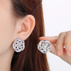 Boucles d'oreilles fleurs ajourées en acier inoxydable avec perle portées par un mannequin