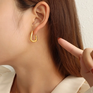 Minimalist C-shaped titanium steel earrings with 18K gold plating on female model