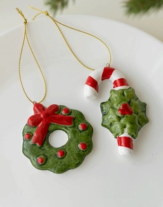 Detail showing ceramic Christmas wreath and candy cane ornaments with golden hanging strings