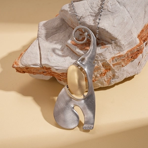 Abstract brushed stainless steel elephant pendant necklace on a natural stone background