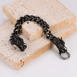 Close-up of vintage silver dragon head bracelet with Cuban chain on stone blocks