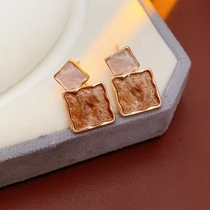 Macro shot of square layered earrings with pink and marble resin in gold metal frames