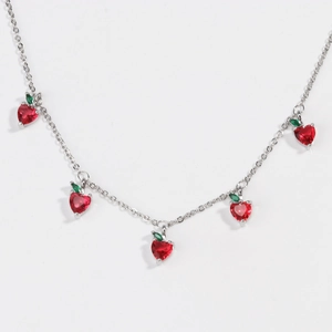 Detailed view of silver chain necklace with red zircon heart charms and green leaf accents