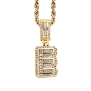 Detail of hip hop letter E pendant with iced out baguette cubic zirconia and gold rope chain