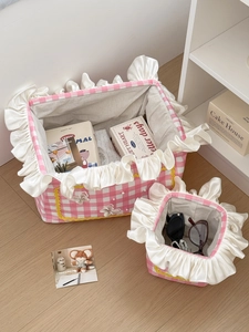 Macro view of pink plaid storage basket with elegant ruffled edges and pearl bow detail