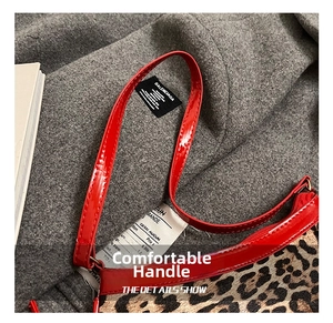 Detail of leopard print handbag featuring red patent leather straps and zip closure