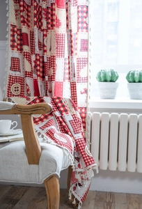 Detail of red and beige patchwork curtain with heart motifs and fringe trim details