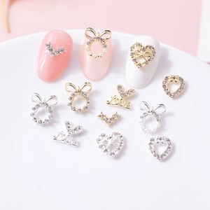 Macro di ciondoli per unghie in lega oro e argento con cuori e fiocchi su sfondo rosa